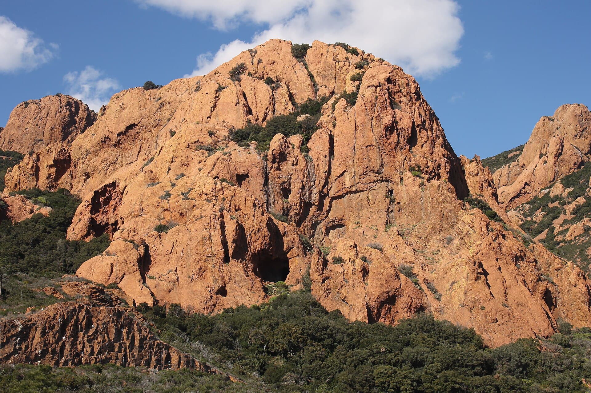 Red cliffs of the Estérel plunging into emerald sea — calanque accessible by boat